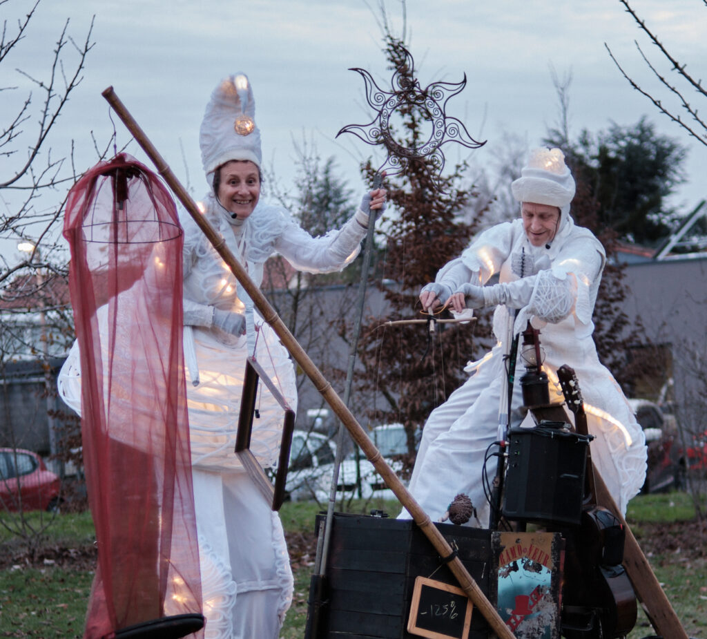 Compagnie de théâtre professionnelle Deux échassiers lumineux blancs, appelés Anges Lumineux, lors d’un spectacle de rue poétique